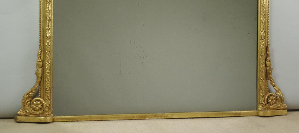An arched Victorian overmantel mirror featuring a gold giltwood frame with a central scrolled crest motif. View X