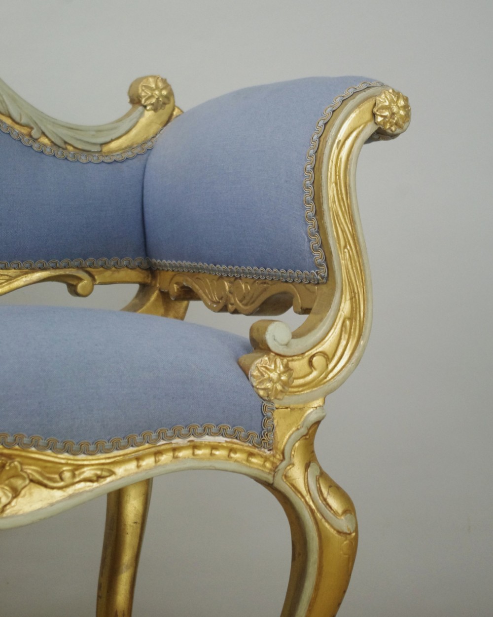 A 19th-century French giltwood occasional chair featuring light blue fabric upholstery, padded scroll arms, carved cresting, and cabriole legs. View VIII