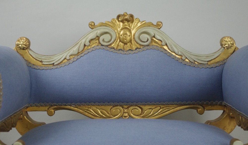 A 19th-century French giltwood occasional chair featuring light blue fabric upholstery, padded scroll arms, carved cresting, and cabriole legs. View IX