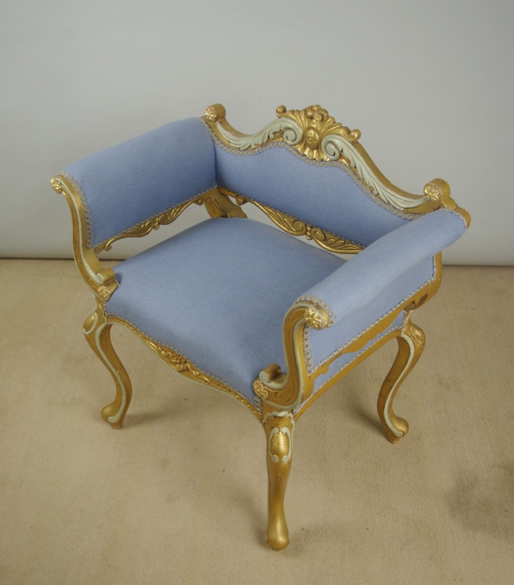 A 19th-century French giltwood occasional chair featuring light blue fabric upholstery, padded scroll arms, carved cresting, and cabriole legs. View XIV