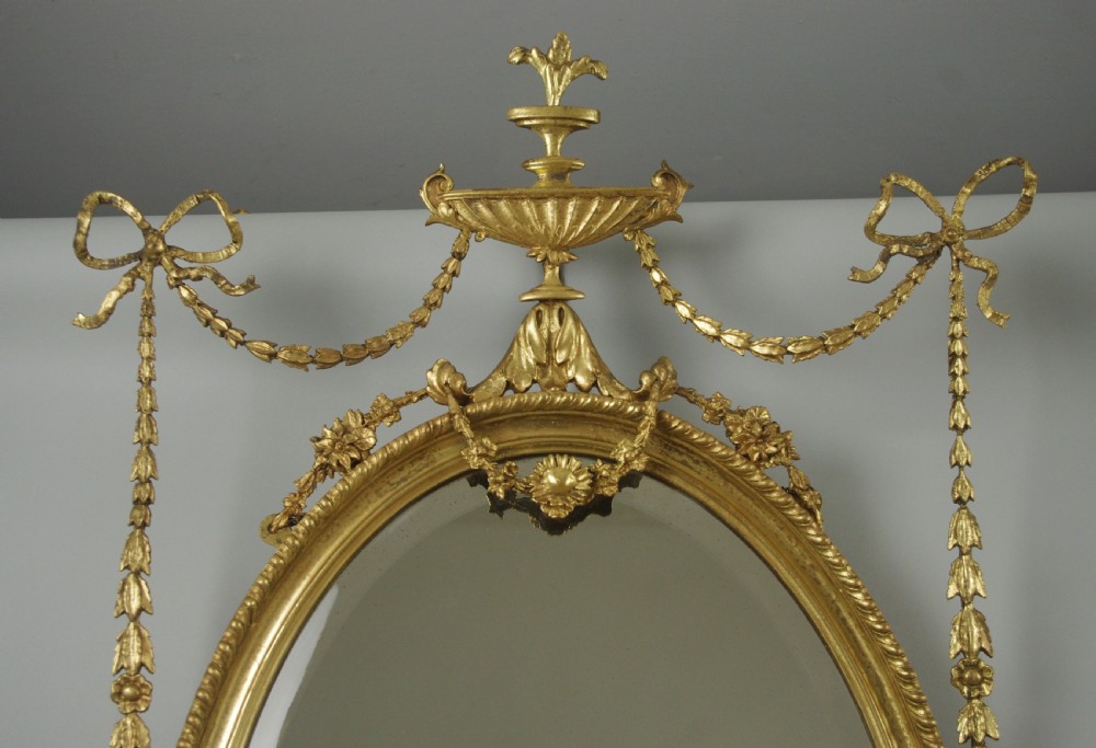 A pair of Victorian giltwood oval wall mirrors topped with urn crestings and ribbon bow swags. View IV