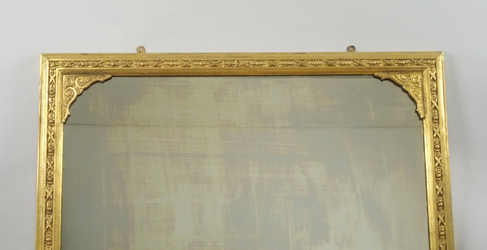 A large Victorian gold gilt overmantel mirror featuring an arched upper frame with beaded moulding and scrolled side feet. View II