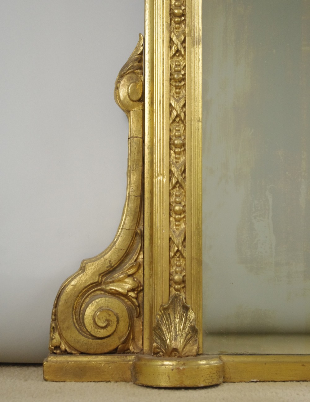 A large Victorian gold gilt overmantel mirror featuring an arched upper frame with beaded moulding and scrolled side feet. View V