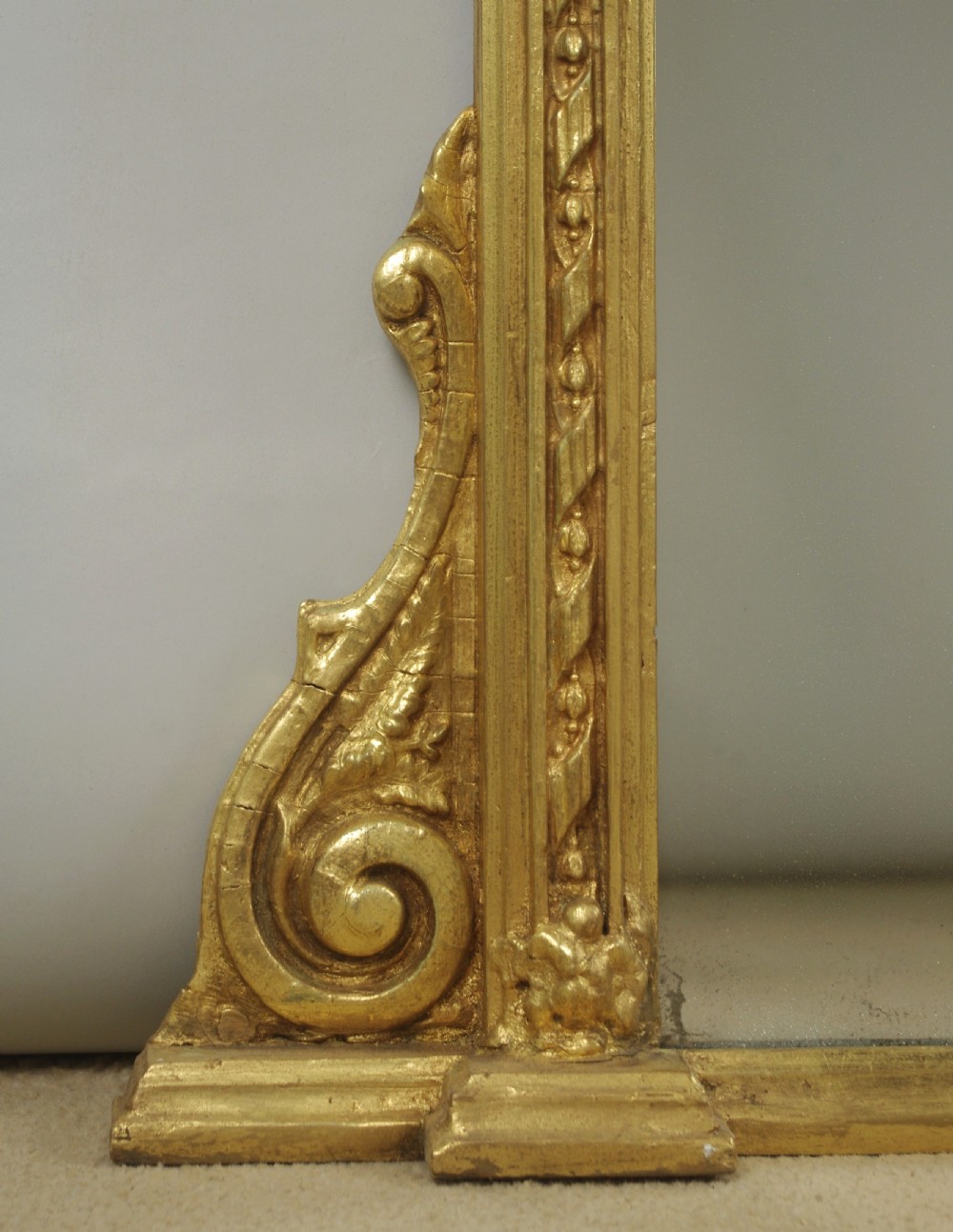 A large Victorian gilt overmantel mirror featuring a rectangular frame with arched upper inner corners, beaded moulding, and scrolled support feet. View VI