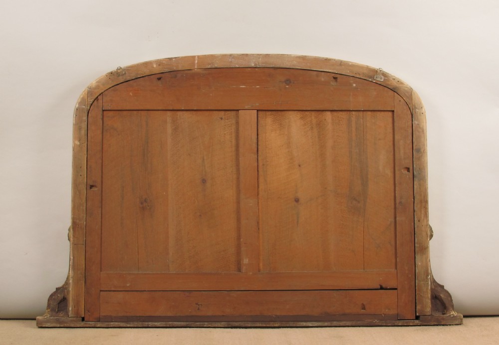 A large Victorian giltwood overmantel mirror with an arched top, beaded moulding frame, and decorative scrolled base corner details. View VIII