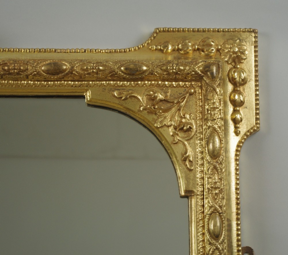 A Victorian giltwood overmantel mirror with an arched frame, central shell crest, and beaded moulding against a neutral backdrop. View IV