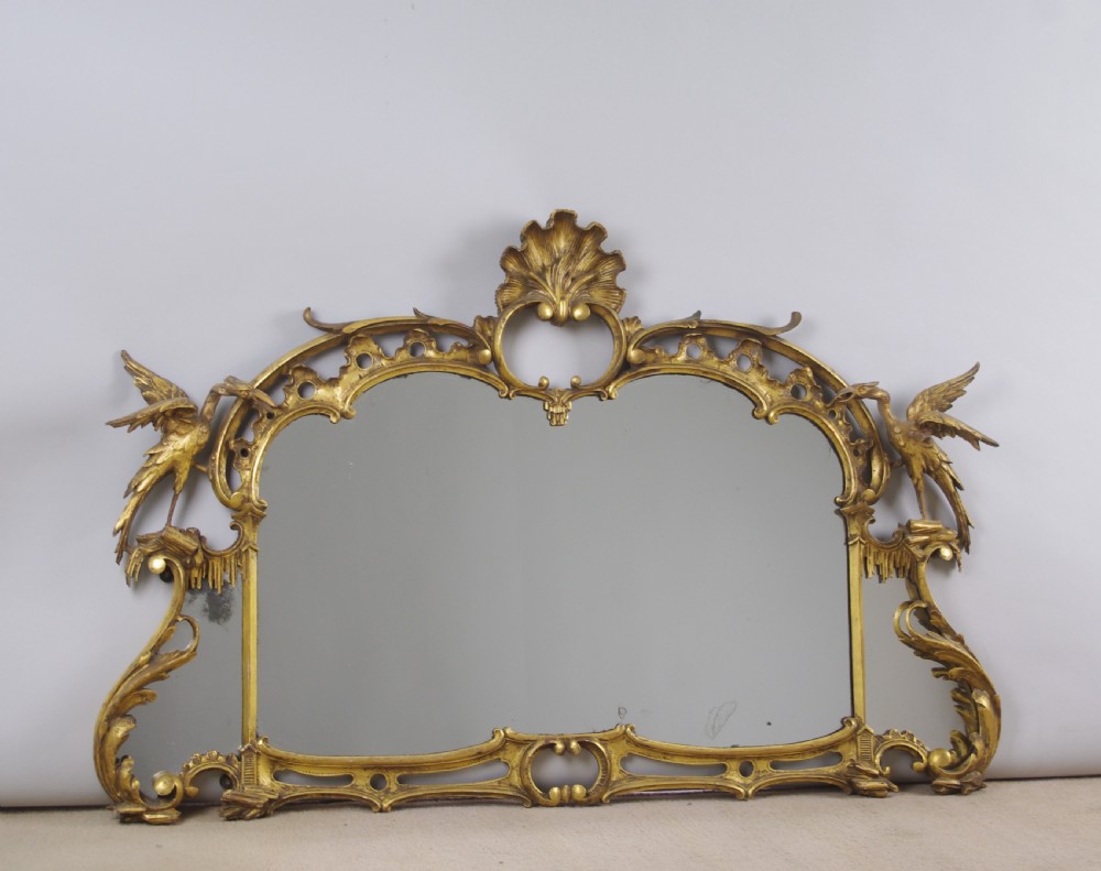 A 19th-century Chinese Chippendale style giltwood overmantel mirror featuring pierced rococo scrollwork, acanthus cresting, and carved exotic birds flanking the central glass.