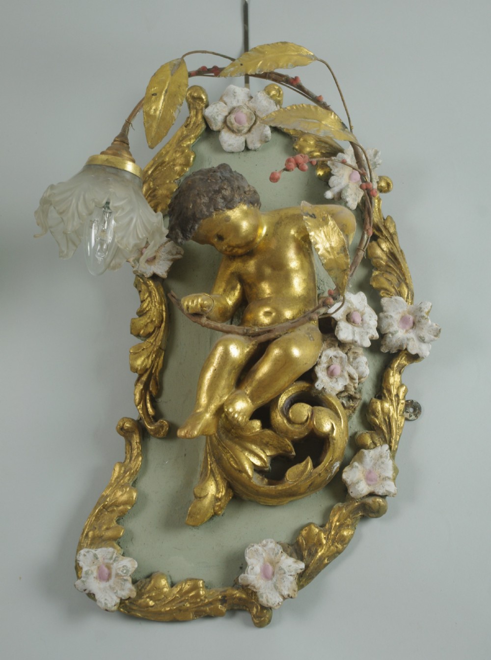 A pair of 19th-century French gilt wall lights featuring sculpted putti figures seated within asymmetrical gilded Rococo floral frames with frosted glass flower shades. View III