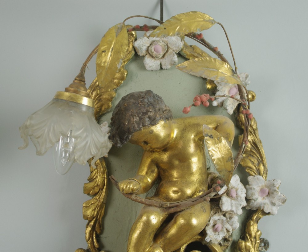 A pair of 19th-century French gilt wall lights featuring sculpted putti figures seated within asymmetrical gilded Rococo floral frames with frosted glass flower shades. View VII