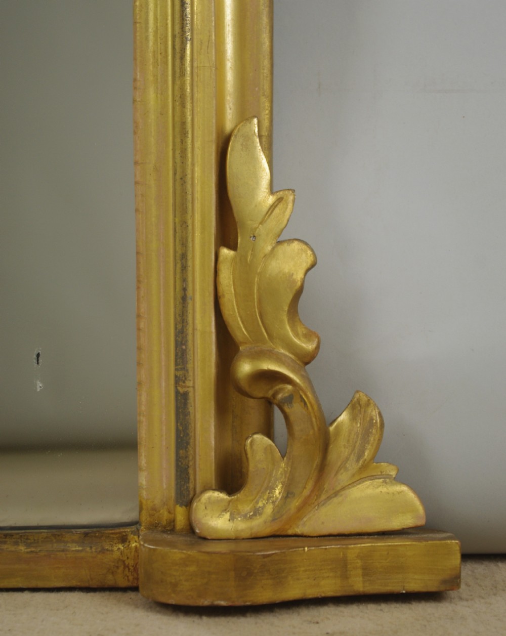 A Victorian giltwood overmantle mirror featuring an arched top frame, carved foliate cresting, and a flat base. View VII