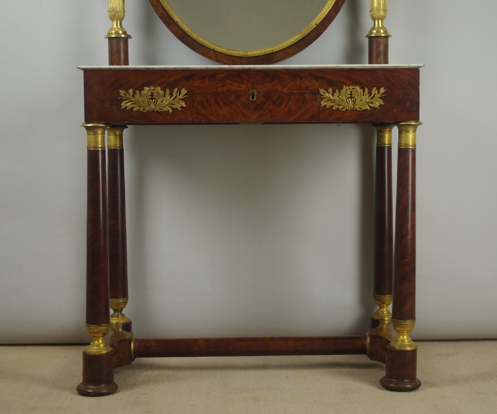 A French Empire mahogany dressing table featuring an oval swivel mirror flanked by gilt-bronze capped columns, set above a marble surface and drawer base with ormolu appliques. View V