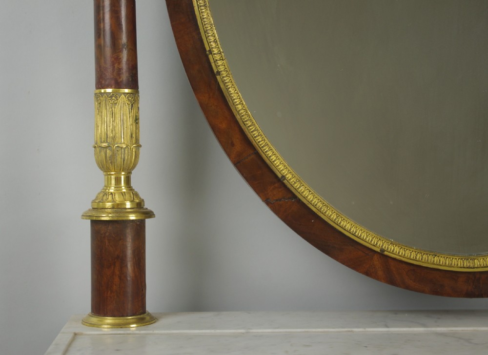 A French Empire mahogany dressing table featuring an oval swivel mirror flanked by gilt-bronze capped columns, set above a marble surface and drawer base with ormolu appliques. View IX