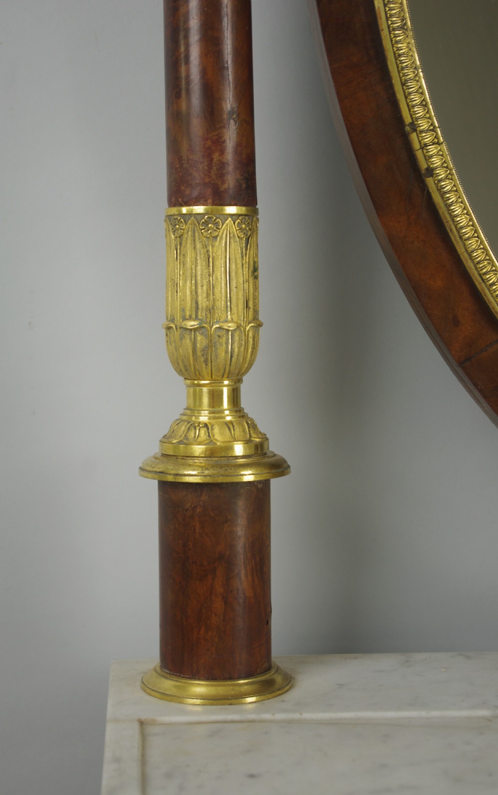 A French Empire mahogany dressing table featuring an oval swivel mirror flanked by gilt-bronze capped columns, set above a marble surface and drawer base with ormolu appliques. View X