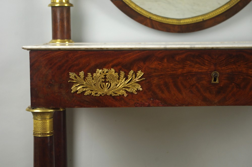 A French Empire mahogany dressing table featuring an oval swivel mirror flanked by gilt-bronze capped columns, set above a marble surface and drawer base with ormolu appliques. View XV