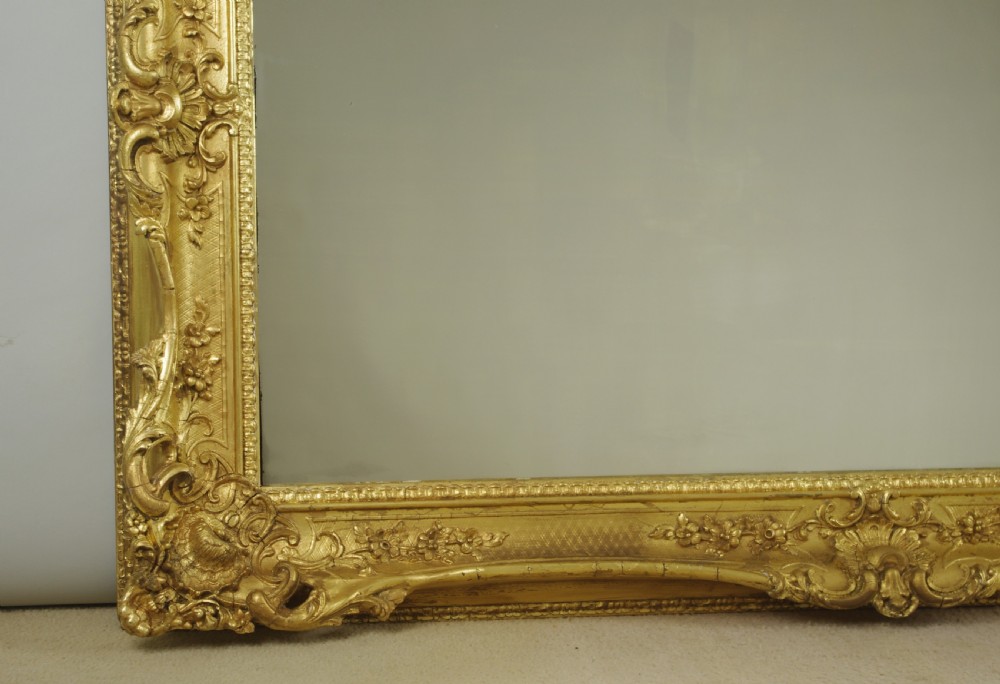 A large rectangular Victorian giltwood wall mirror featuring an ornate swept frame with shell and scroll corner mouldings. View IV