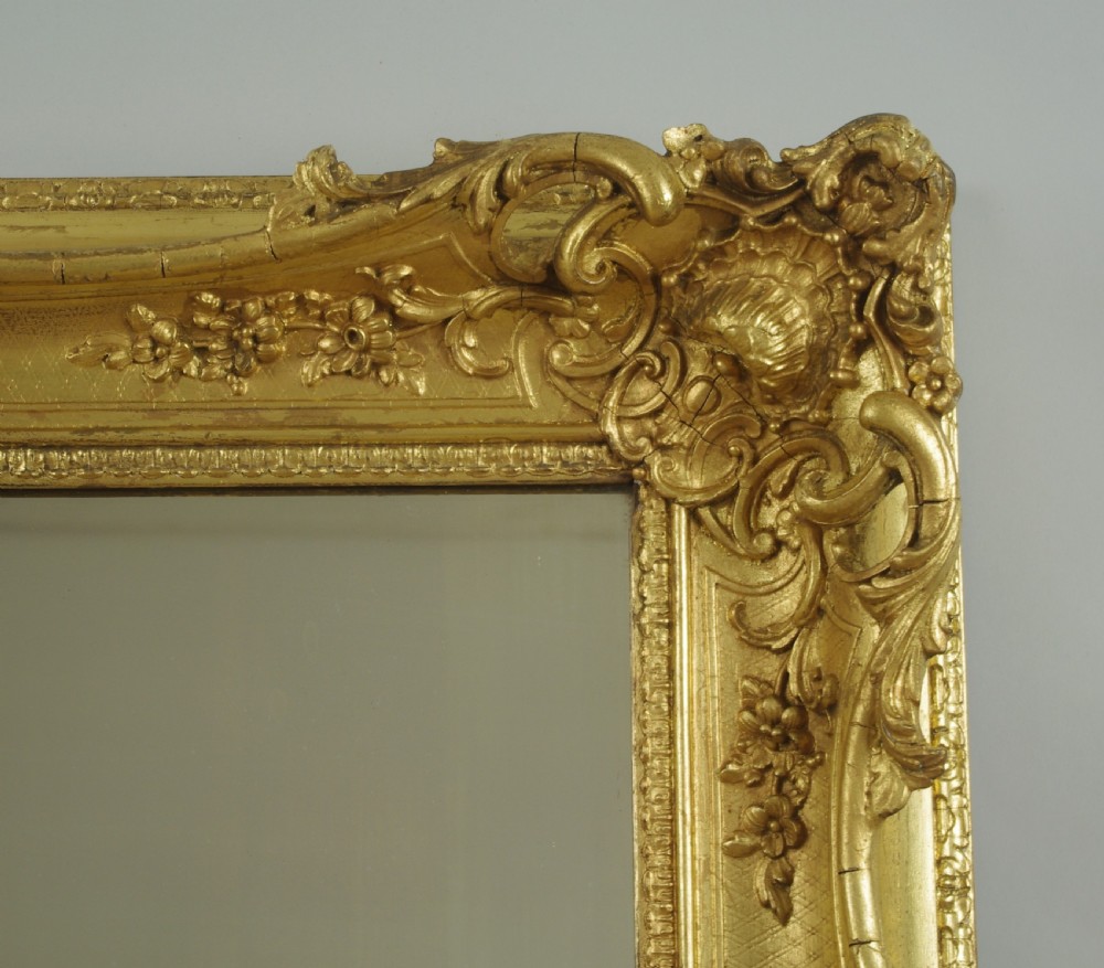 A large rectangular Victorian giltwood wall mirror featuring an ornate swept frame with shell and scroll corner mouldings. View VIII