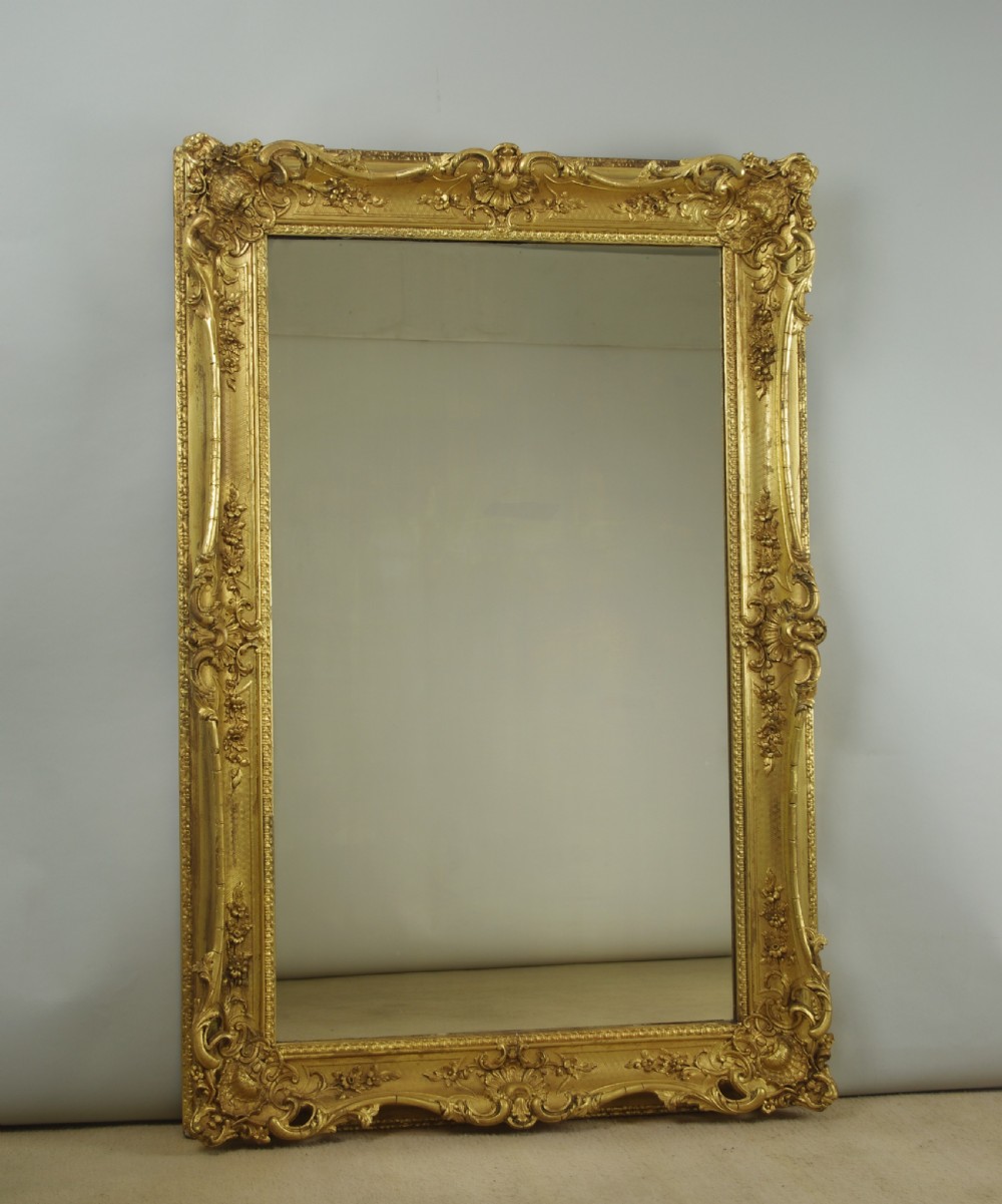 A large rectangular Victorian giltwood wall mirror featuring an ornate swept frame with shell and scroll corner mouldings. View XII