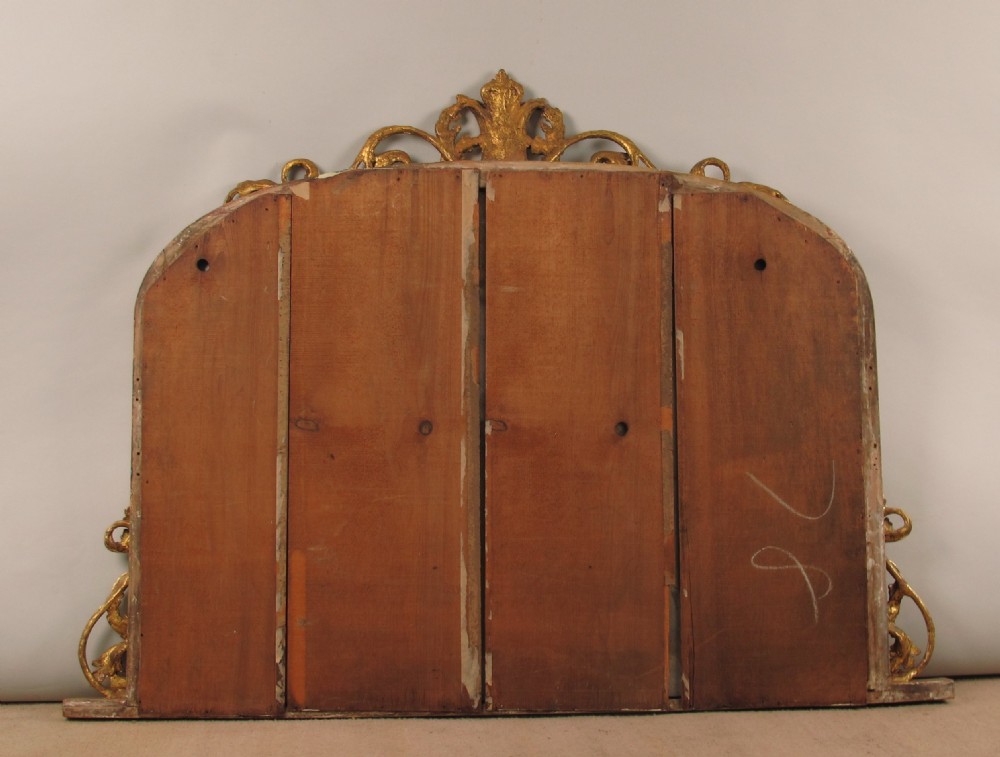 A Victorian giltwood overmantel mirror with an arched frame, central acanthus leaf cresting, twisted rope moulding, and scrolling side brackets. View X