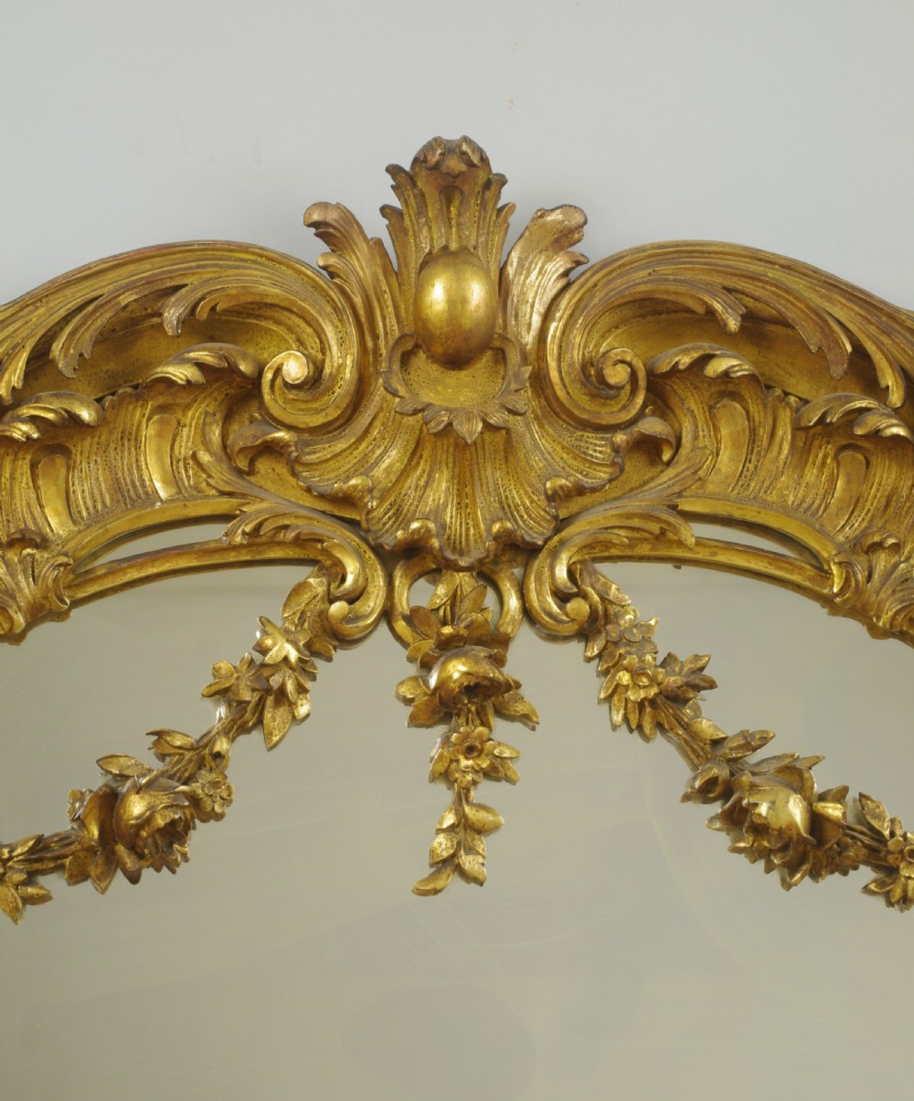 A 19th-century Rococo style giltwood overmantel mirror featuring three mirror plates, carved floral garlands, and a cresting. View VII