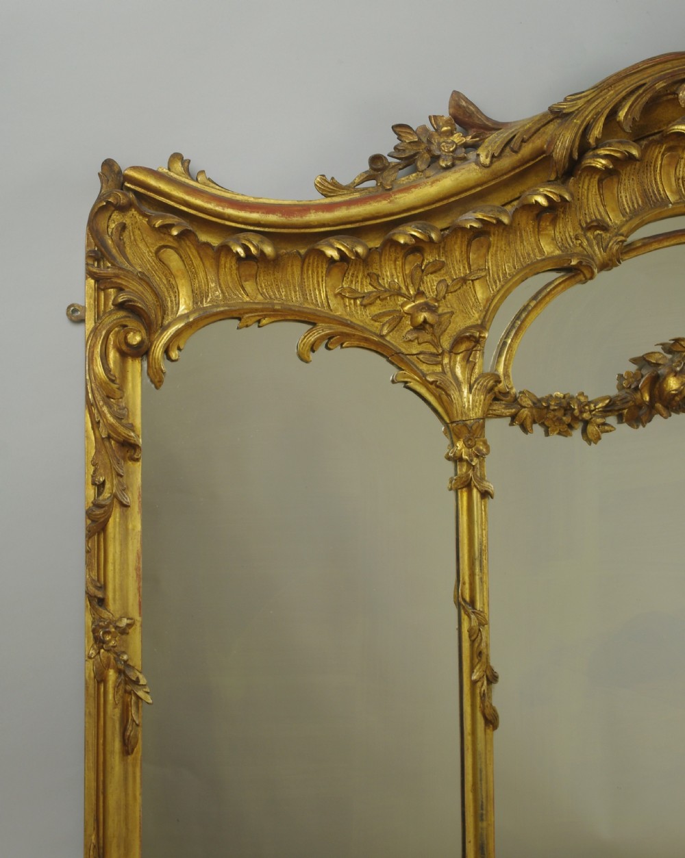 A 19th-century Rococo style giltwood overmantel mirror featuring three mirror plates, carved floral garlands, and a cresting. View VIII