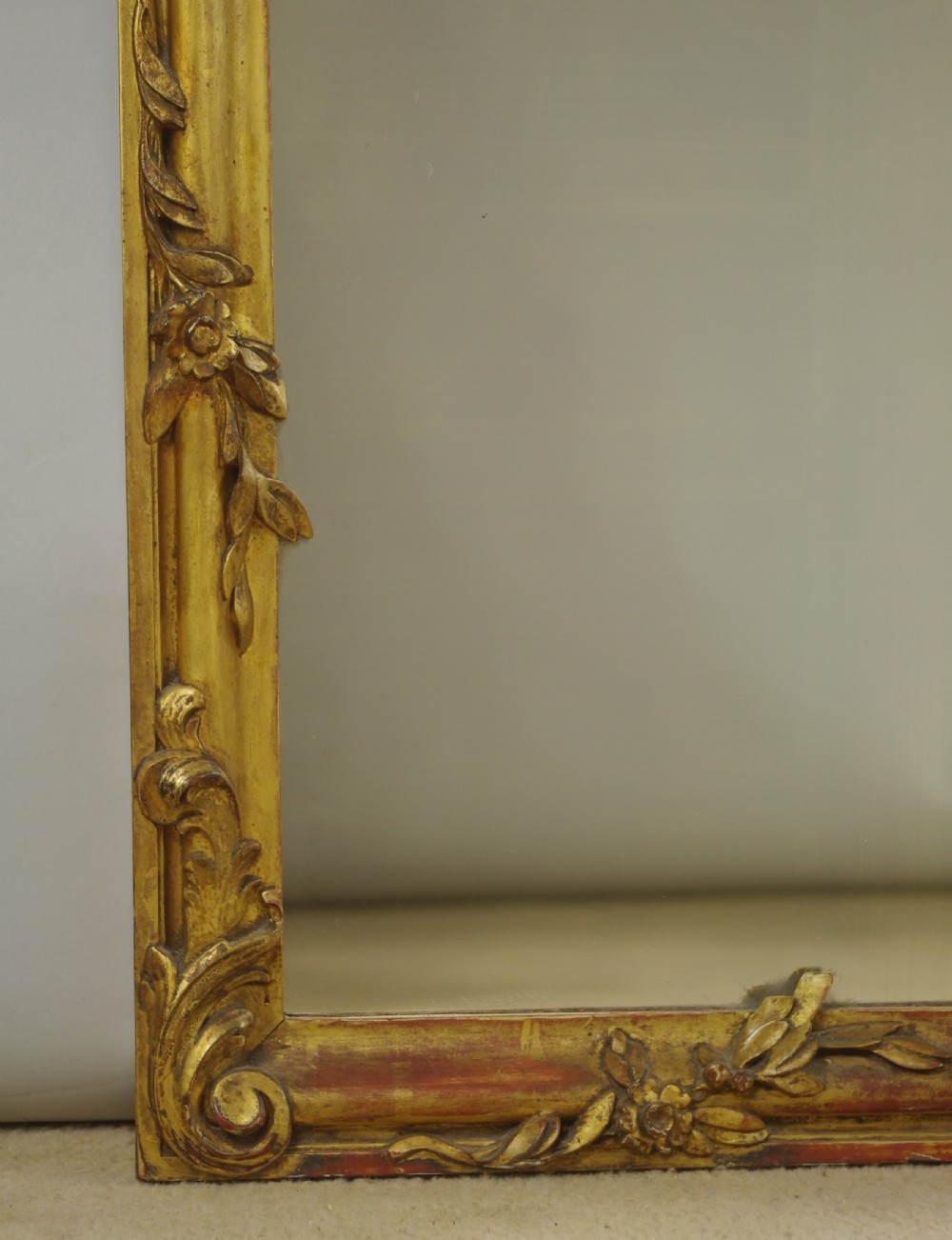 A 19th-century Rococo style giltwood overmantel mirror featuring three mirror plates, carved floral garlands, and a cresting. View X