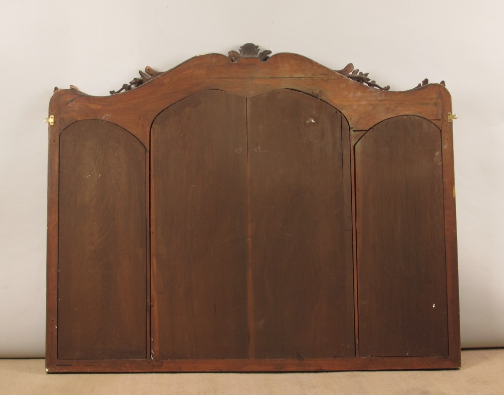 A 19th-century Rococo style giltwood overmantel mirror featuring three mirror plates, carved floral garlands, and a cresting. View XI