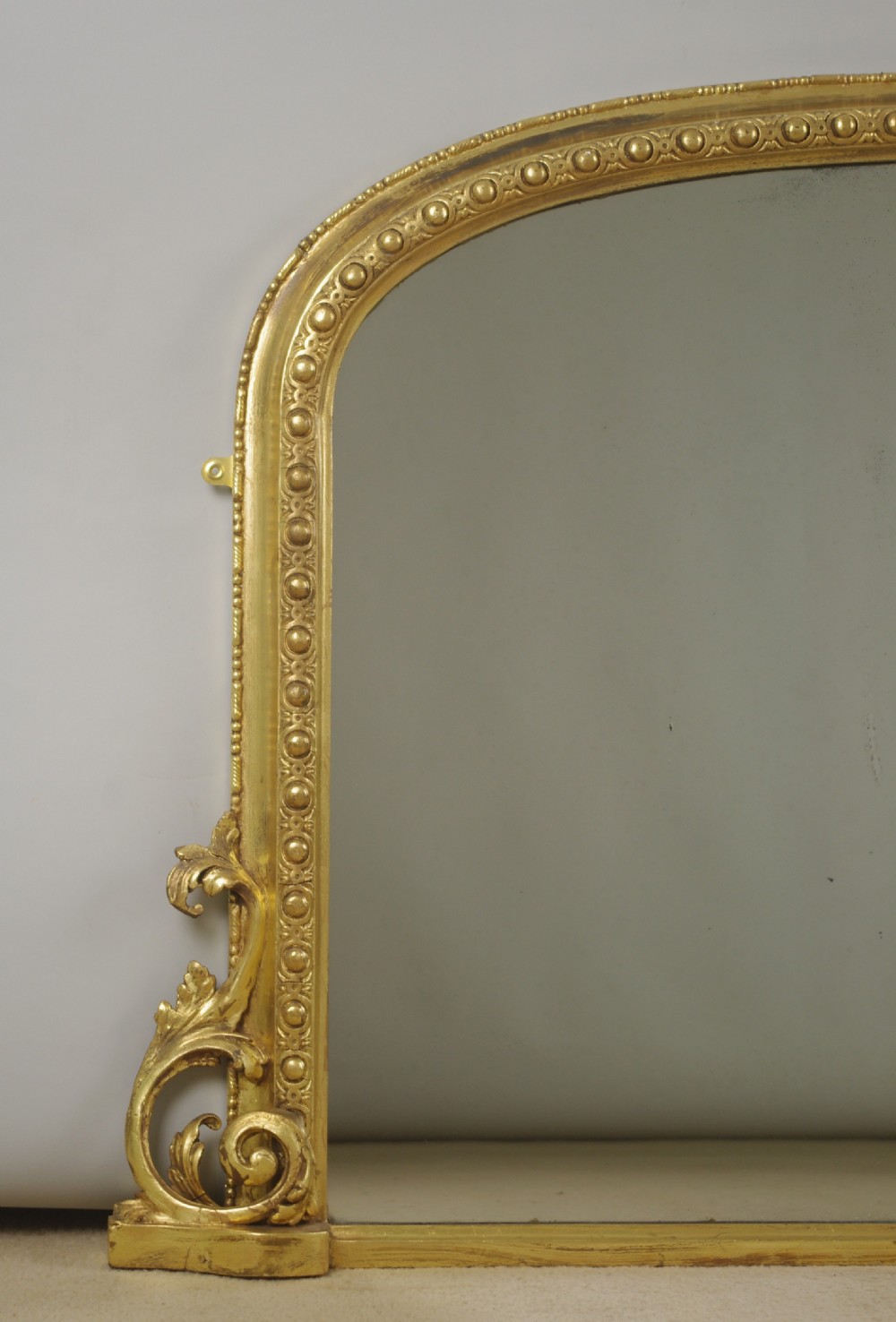An arched Victorian overmantel mirror featuring a gilded frame with beaded moulding and scrollwork side supports. View II