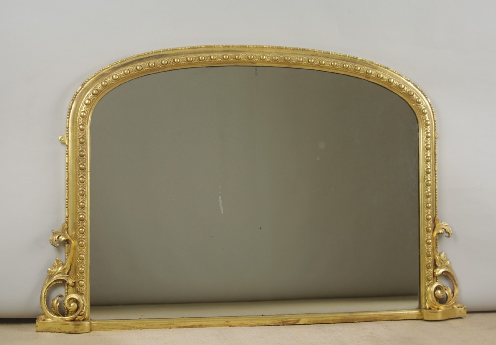 An arched Victorian overmantel mirror featuring a gilded frame with beaded moulding and scrollwork side supports. View VII