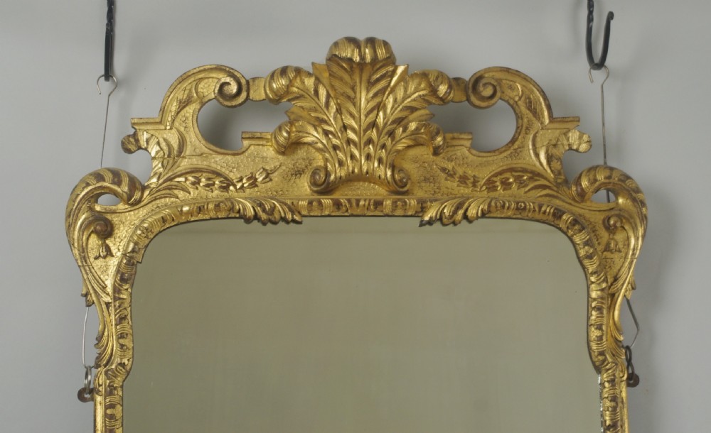 A rectangular 19th-century giltwood wall mirror featuring carved acanthus leaf cresting and scroll details in an aged gold finish. View II