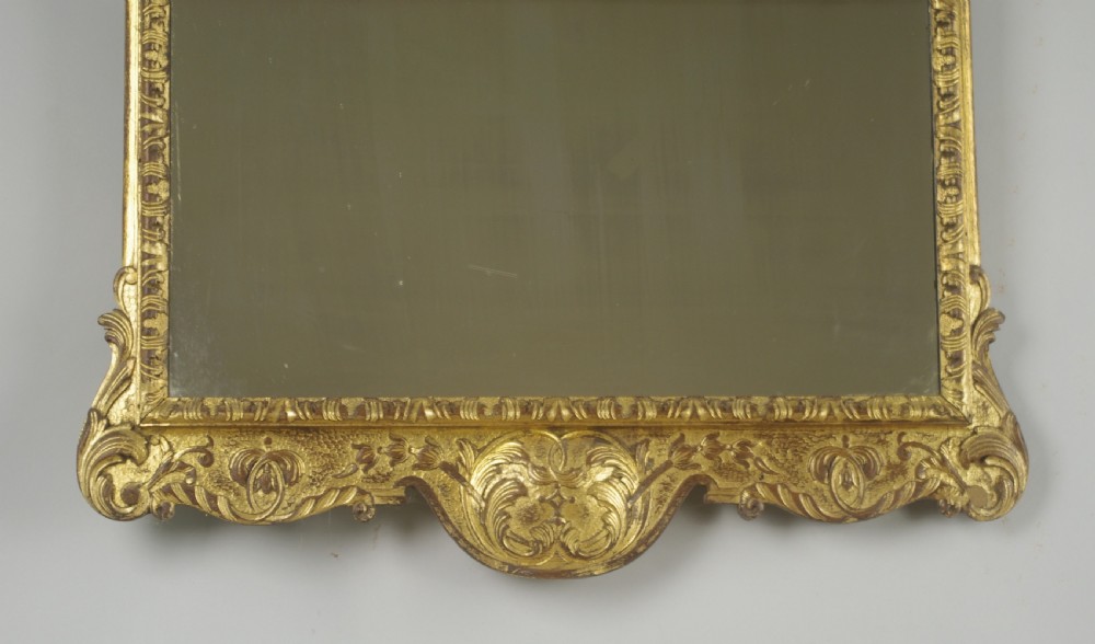 A rectangular 19th-century giltwood wall mirror featuring carved acanthus leaf cresting and scroll details in an aged gold finish. View V
