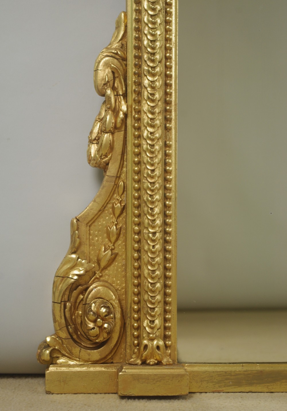 A large Victorian arched overmantel mirror featuring a gilt frame decorated with beaded moulding and scrolled corbels at the base. View V