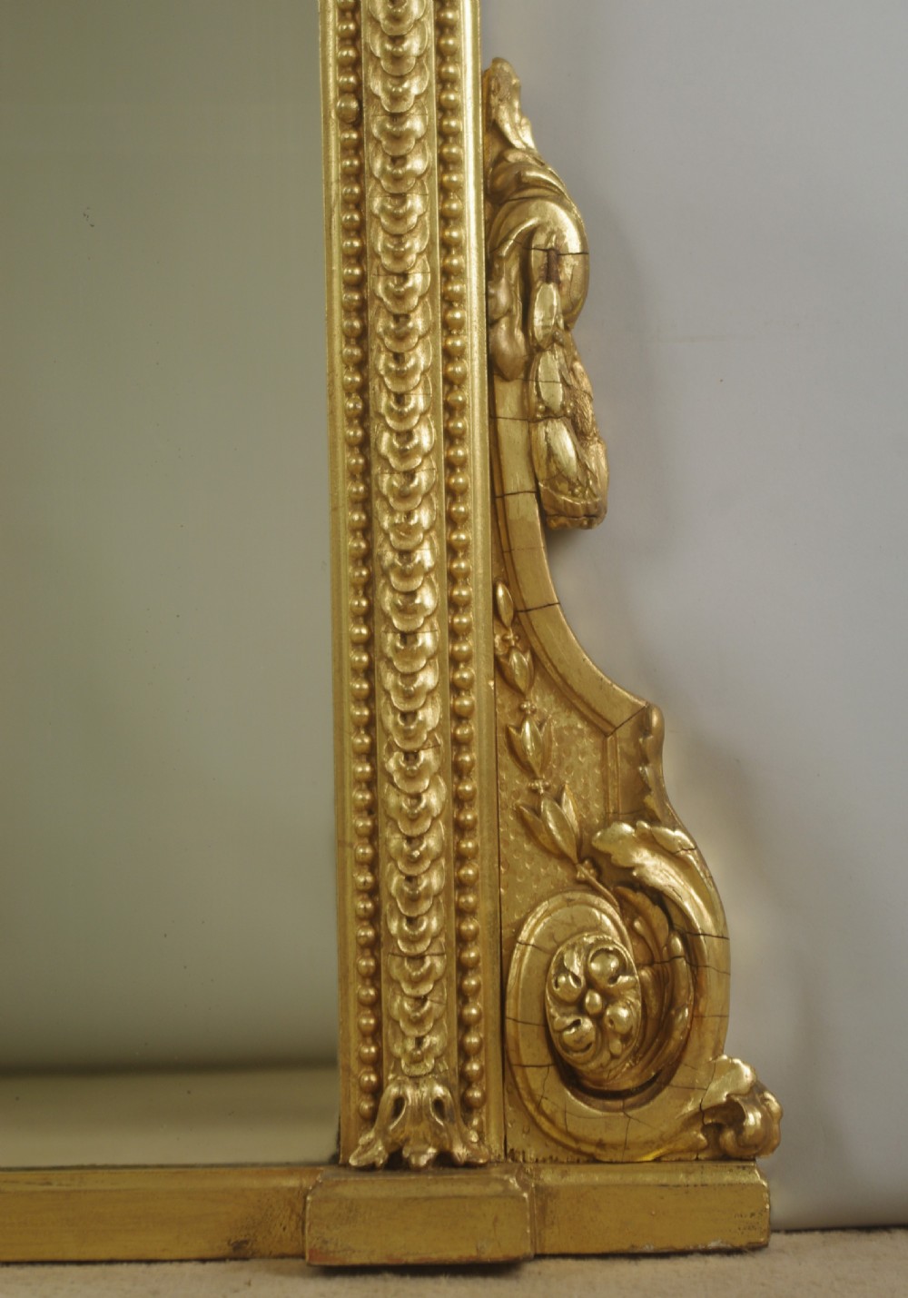 A large Victorian arched overmantel mirror featuring a gilt frame decorated with beaded moulding and scrolled corbels at the base. View VI