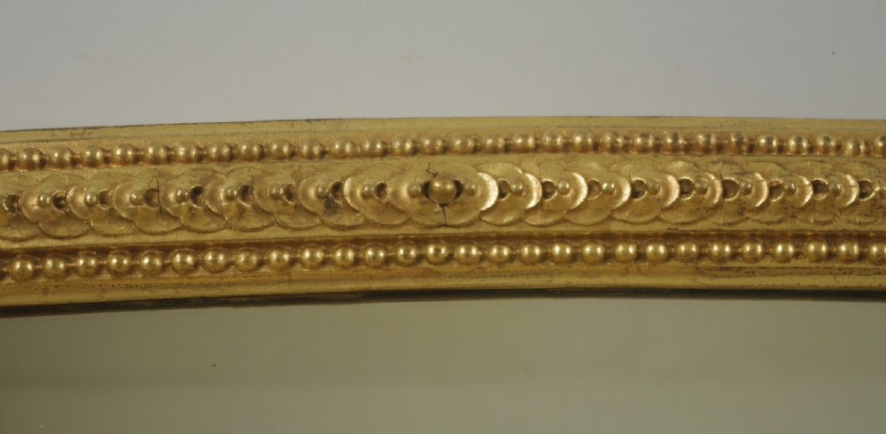A large Victorian arched overmantel mirror featuring a gilt frame decorated with beaded moulding and scrolled corbels at the base. View VIII