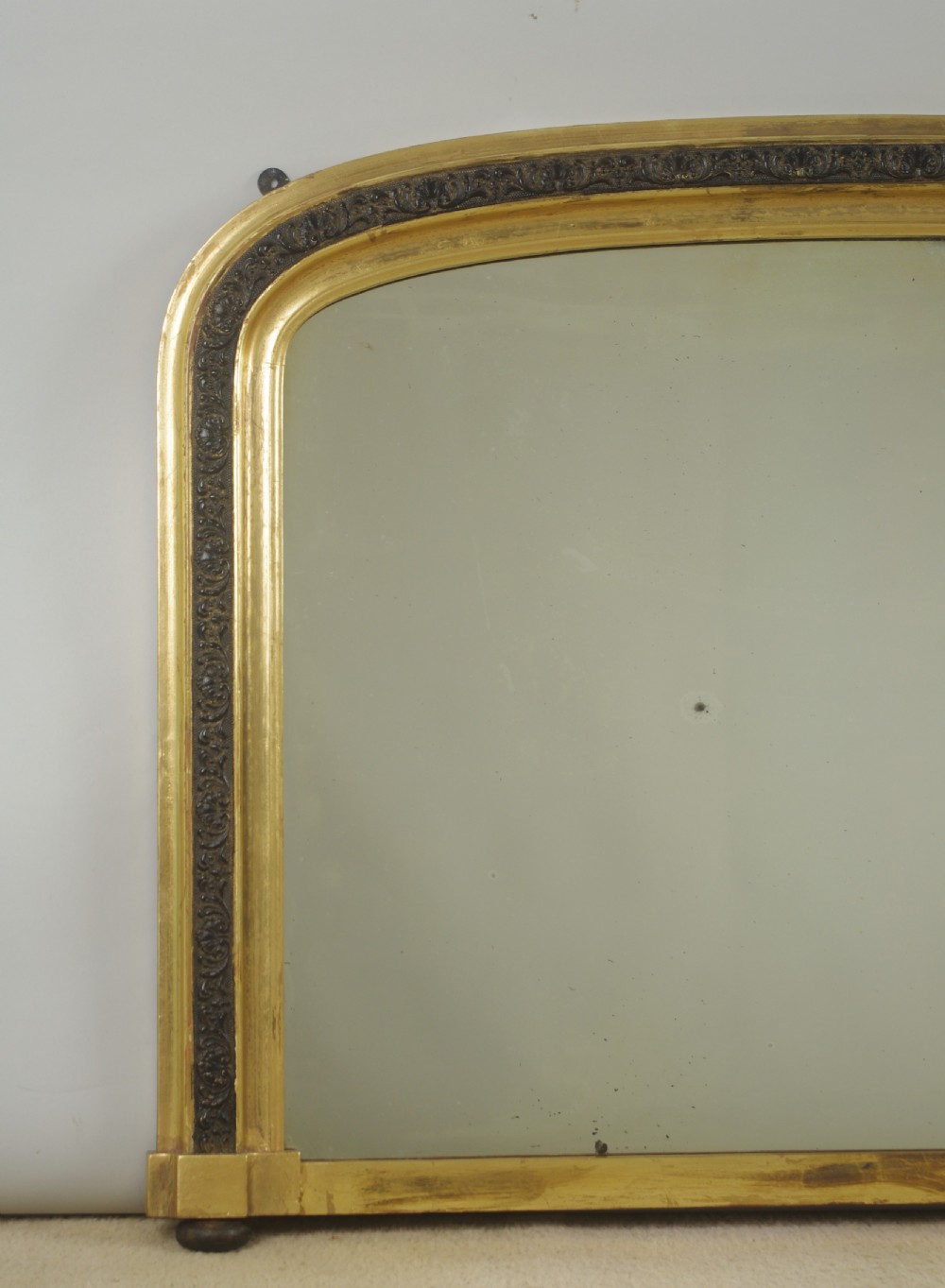 A Victorian arched overmantle mirror featuring a gilt outer frame and an inner carved ebonised moulding band. View II