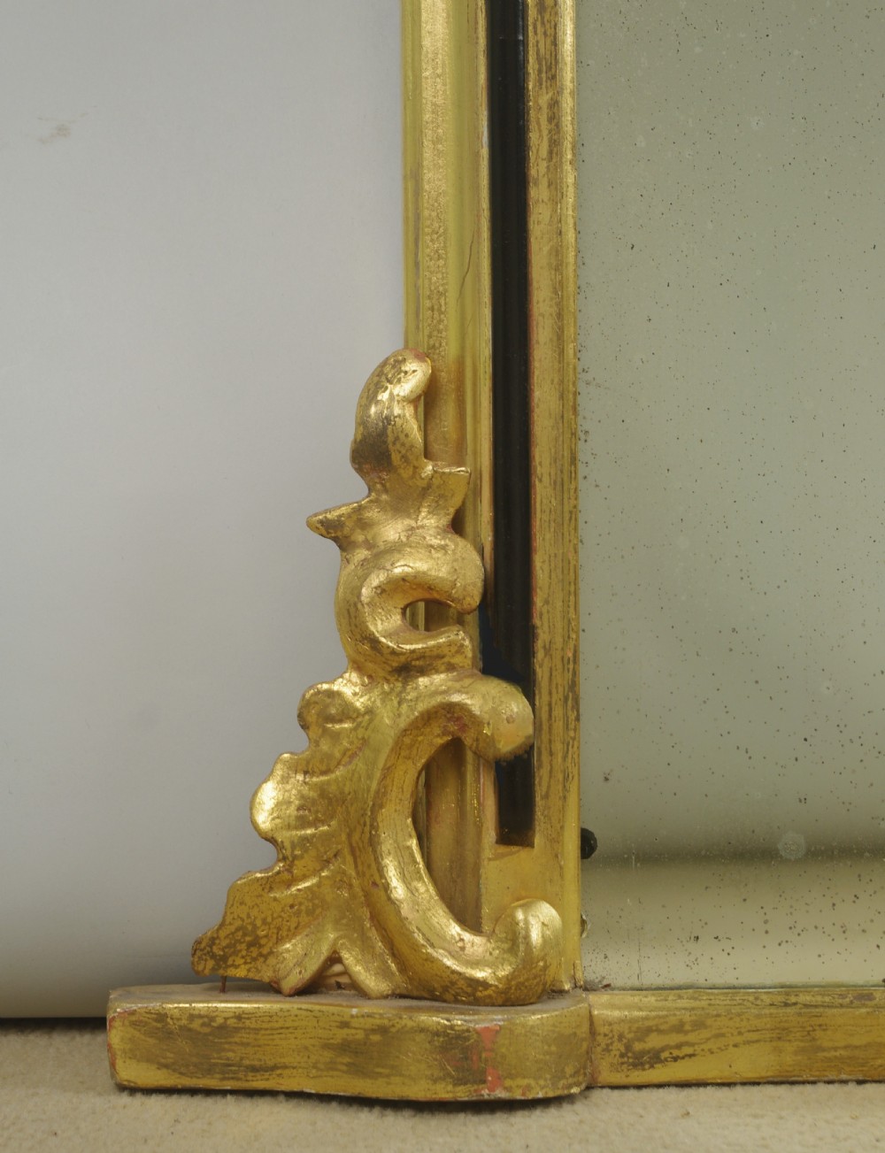 A Victorian arched overmantel mirror featuring a gilded outer frame with an ebonised inner border and carved side scrolls. View V
