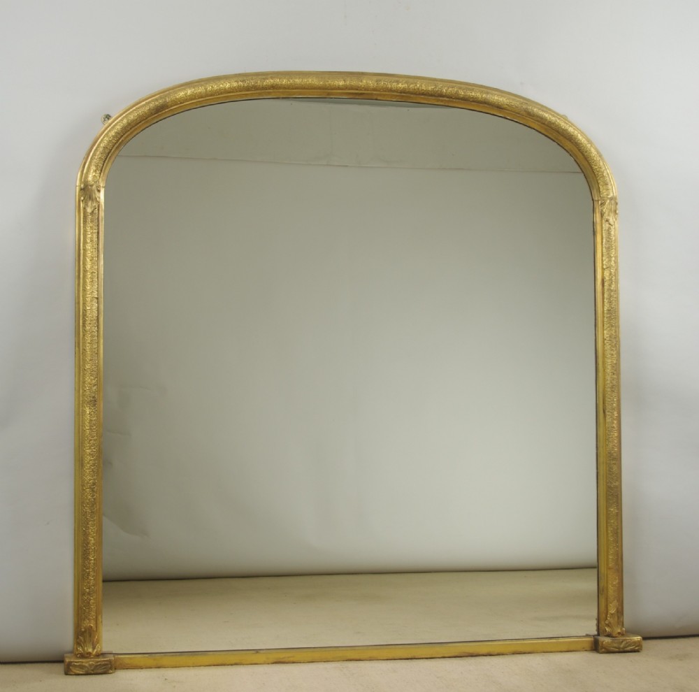 A large Victorian arch top overmantel mirror featuring a moulded gilt frame and flat base.