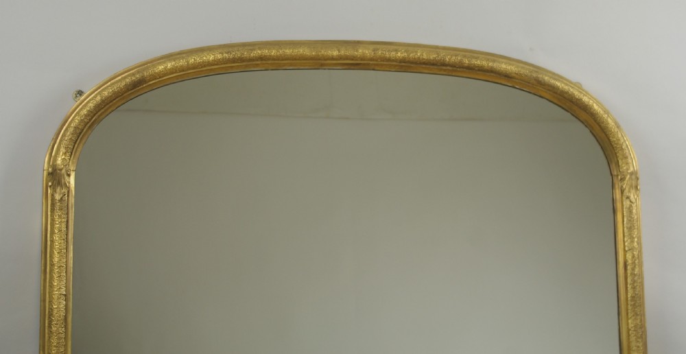 A large Victorian arch top overmantel mirror featuring a moulded gilt frame and flat base. View II