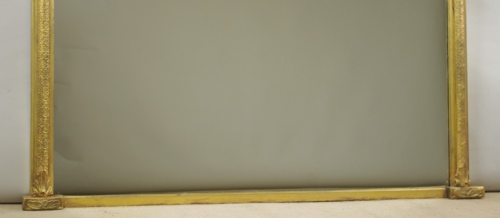 A large Victorian arch top overmantel mirror featuring a moulded gilt frame and flat base. View VII