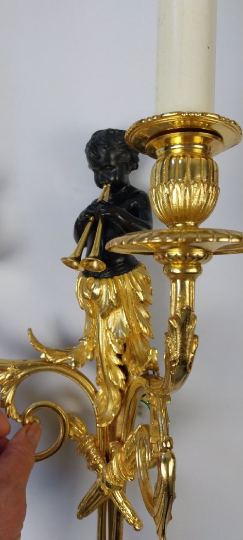 A pair of French gilt and dark patinated bronze two-branch wall sconces featuring central figures holding musical instruments. View II