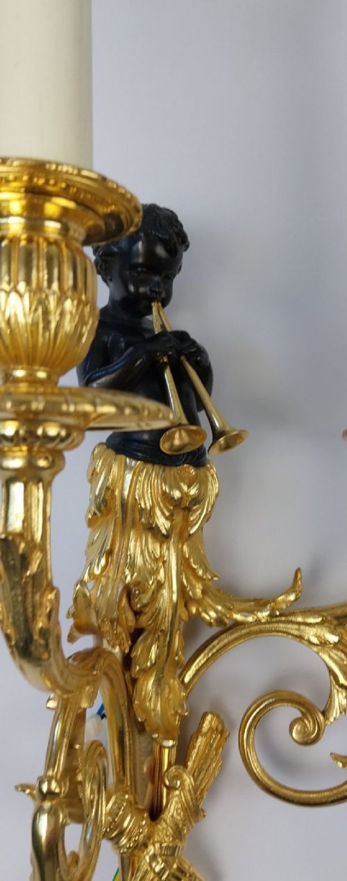 A pair of French gilt and dark patinated bronze two-branch wall sconces featuring central figures holding musical instruments. View IV