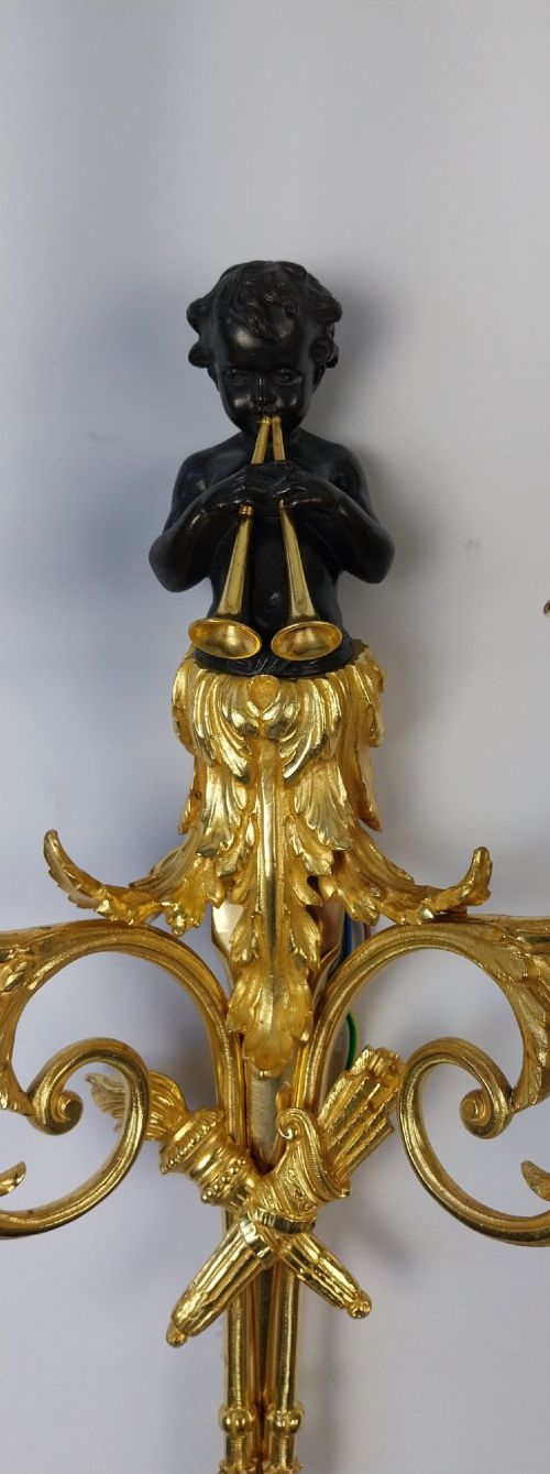 A pair of French gilt and dark patinated bronze two-branch wall sconces featuring central figures holding musical instruments. View VI