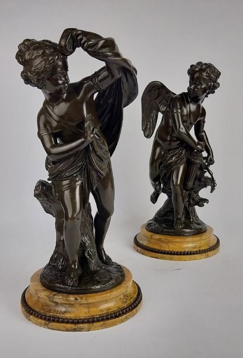 fig 1. A pair of dark patinated bronze sculptures depicting the classical figures Cupid and Psyche set upon round yellow marble bases.