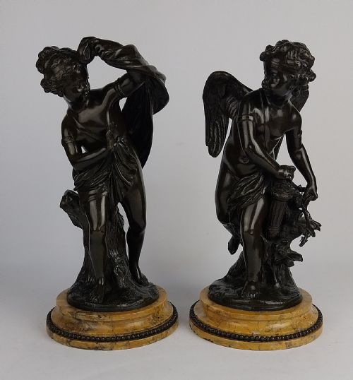 fig 2. A pair of dark patinated bronze sculptures depicting the classical figures Cupid and Psyche set upon round yellow marble bases.