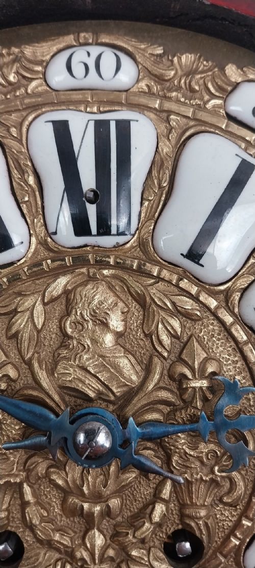 fig 6. An antique French Rococo revival Boulle wall clock featuring a red tortoiseshell case adorned with elaborate gilt bronze mounts, a figure finial, and an enamel cartouche dial on a matching wall bracket.