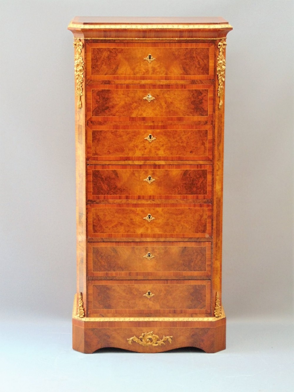 A stunning walnut pedestal wellington chest of drawers