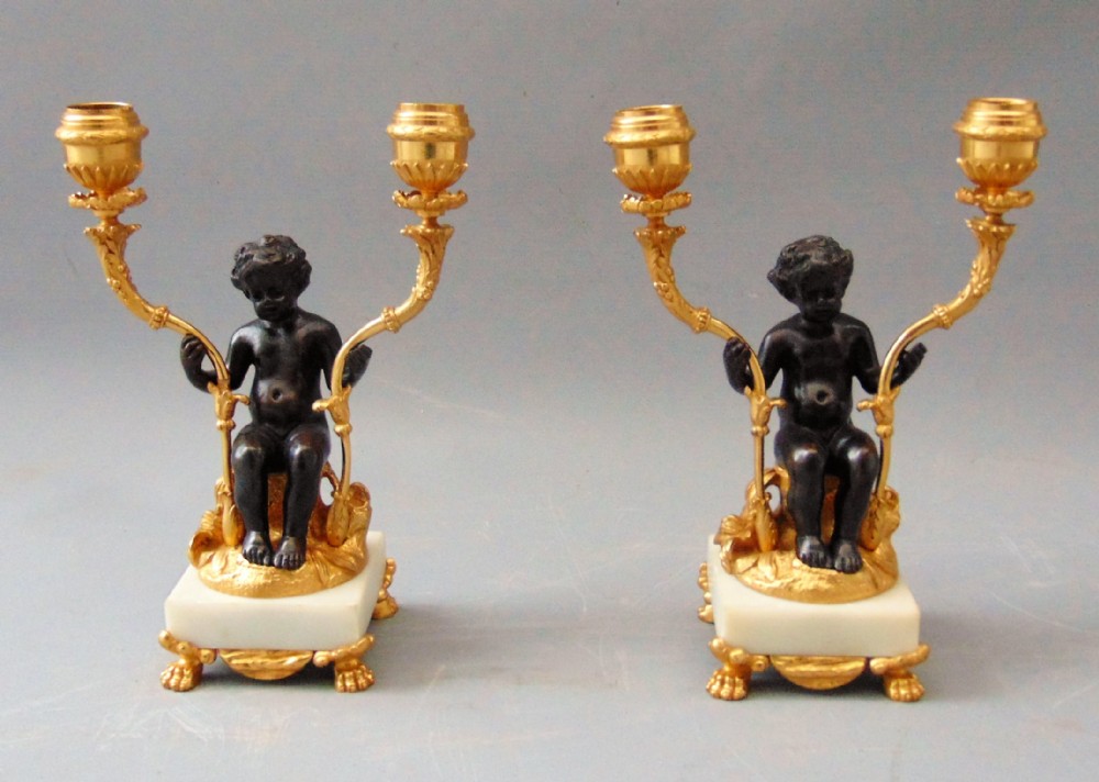A Pair of Bronze and Ormolu Cherub Candlesticks 
