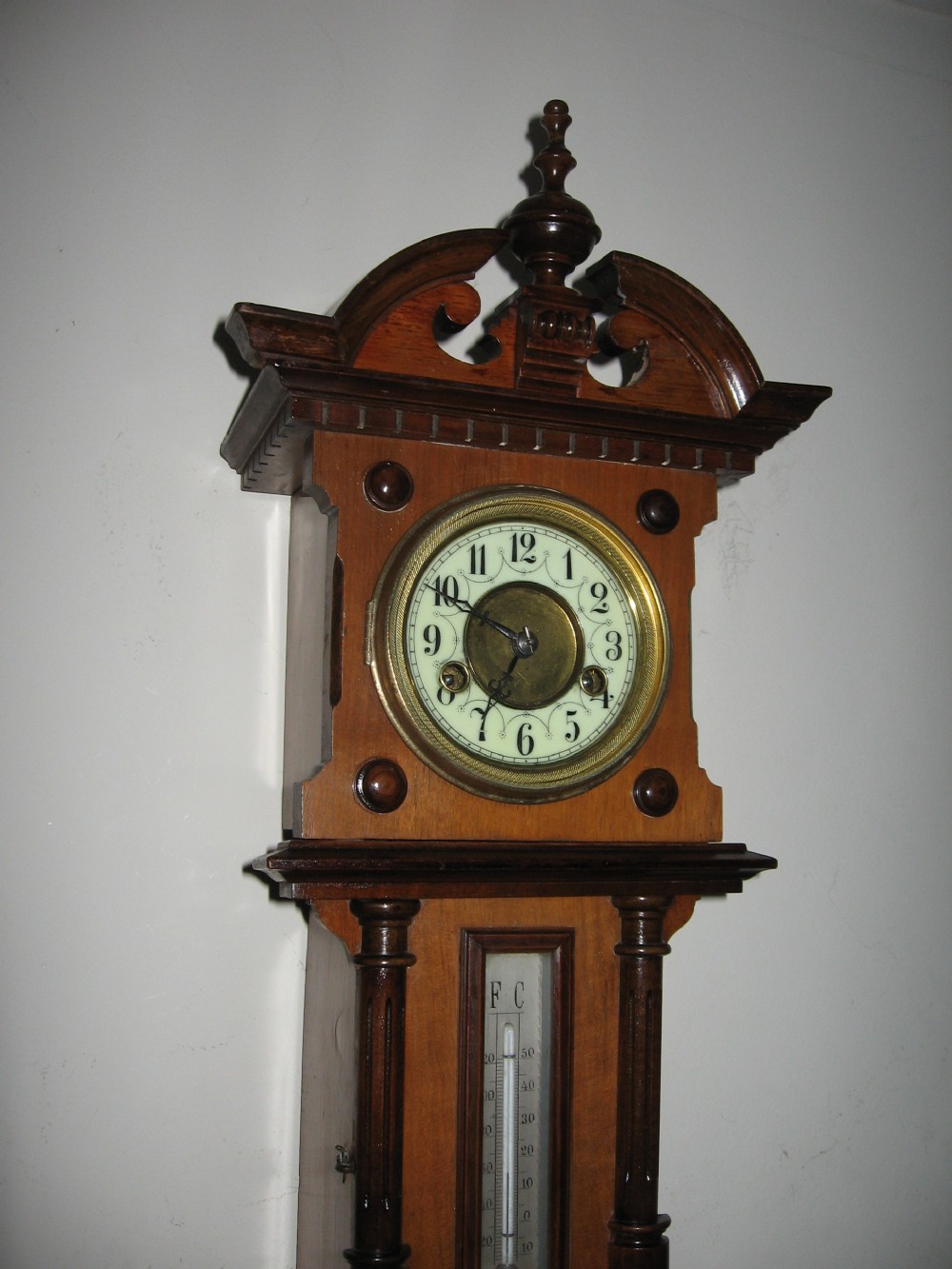A late Victorian carved wooden wall clock featuring an upper clock face, a central thermometer, and a lower barometer dial. View IX