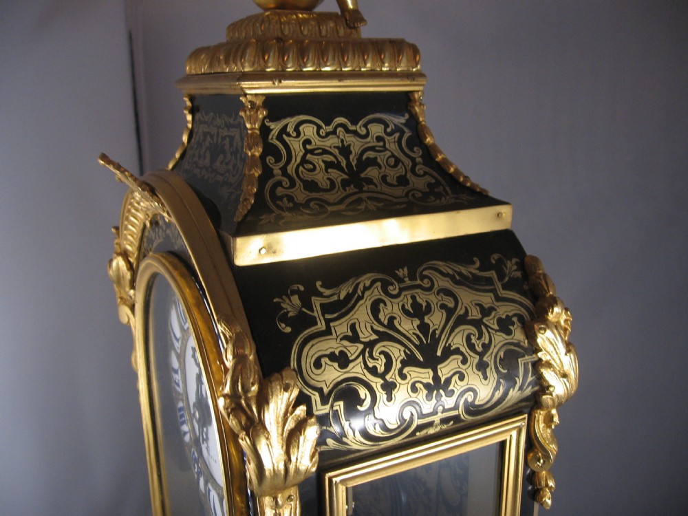 An ornate French Boulle mantel clock decorated with brass marquetry, gilt bronze mounts, a winged cherub finial, and white enamel Roman numeral cartouches. View VII
