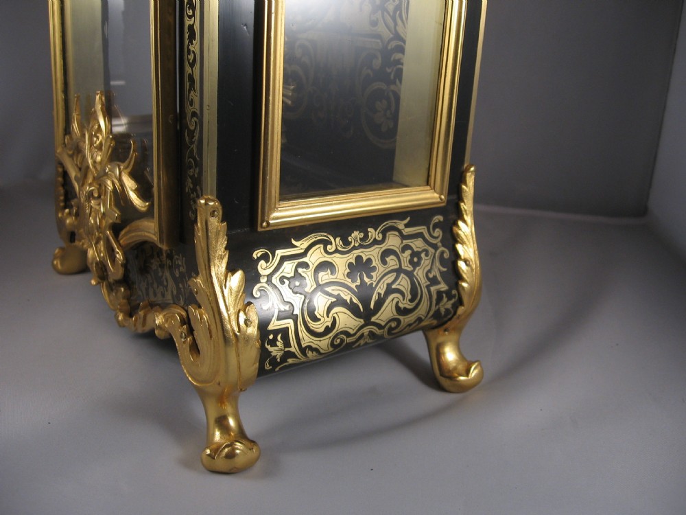An ornate French Boulle mantel clock decorated with brass marquetry, gilt bronze mounts, a winged cherub finial, and white enamel Roman numeral cartouches. View VIII