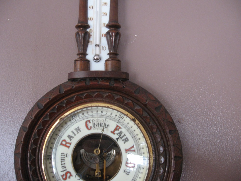 A carved dark walnut wall barometer featuring a vertical thermometer at the top and a circular aneroid pressure dial at the base. View II